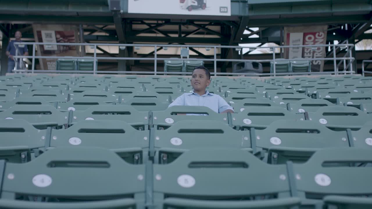 A young person seated in a baseball stadium, from the CASA brand film